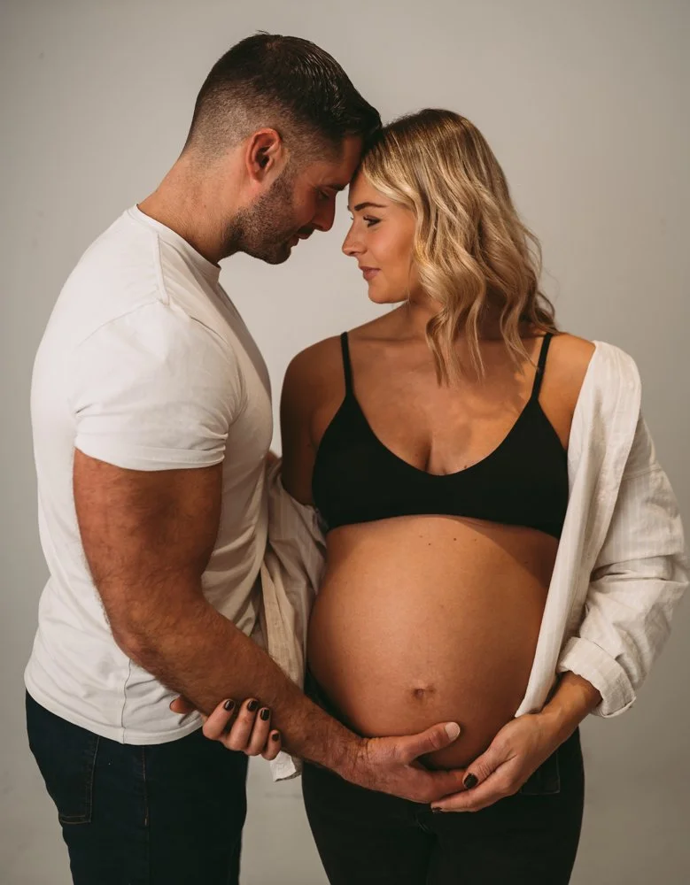 a mother and father to be looking at each other and holding baby bump in black and white clothing, Maternity photography by kp-photo, based in Wiltshire