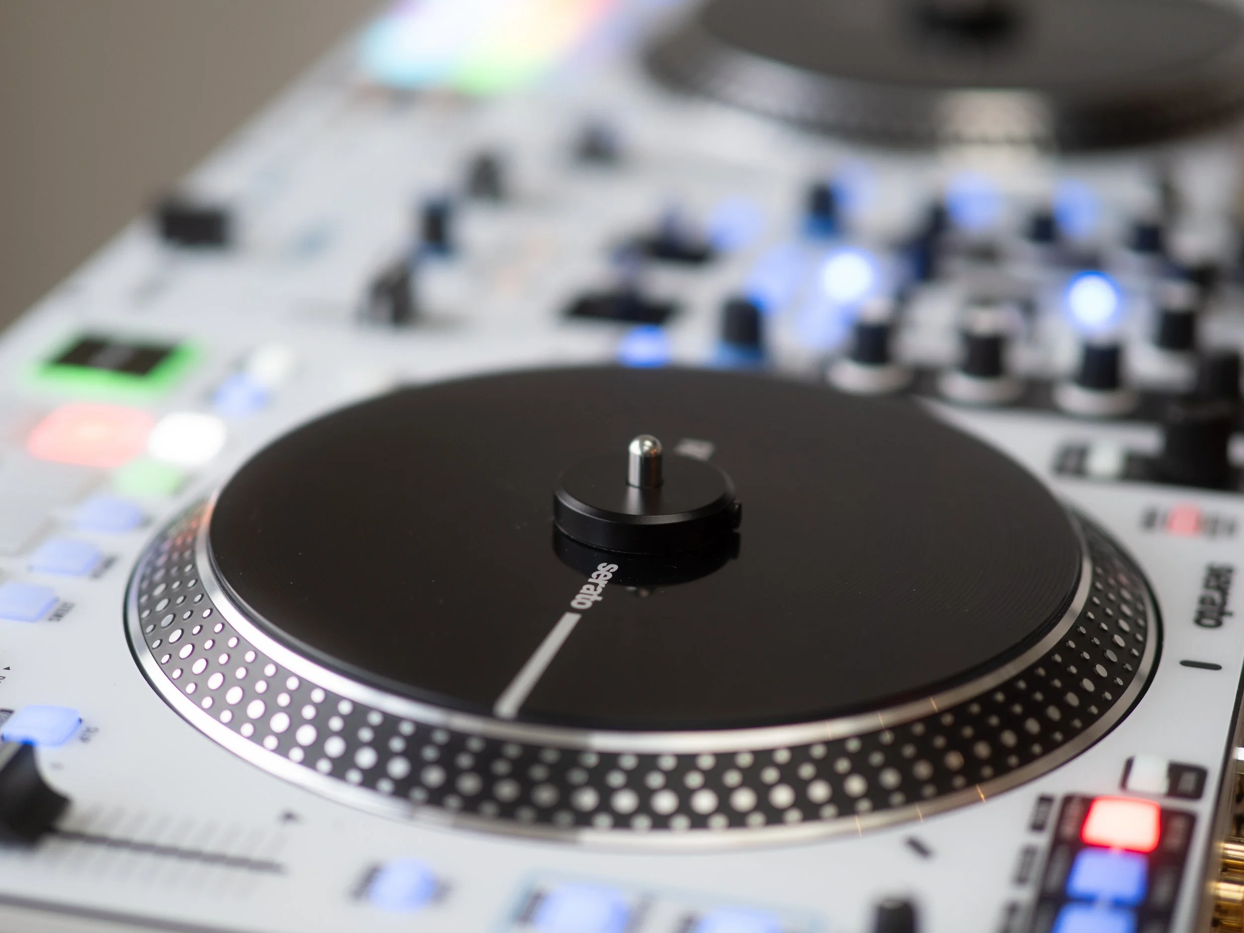 Close-up of a DJ mixing console with a black turntable in the foreground.