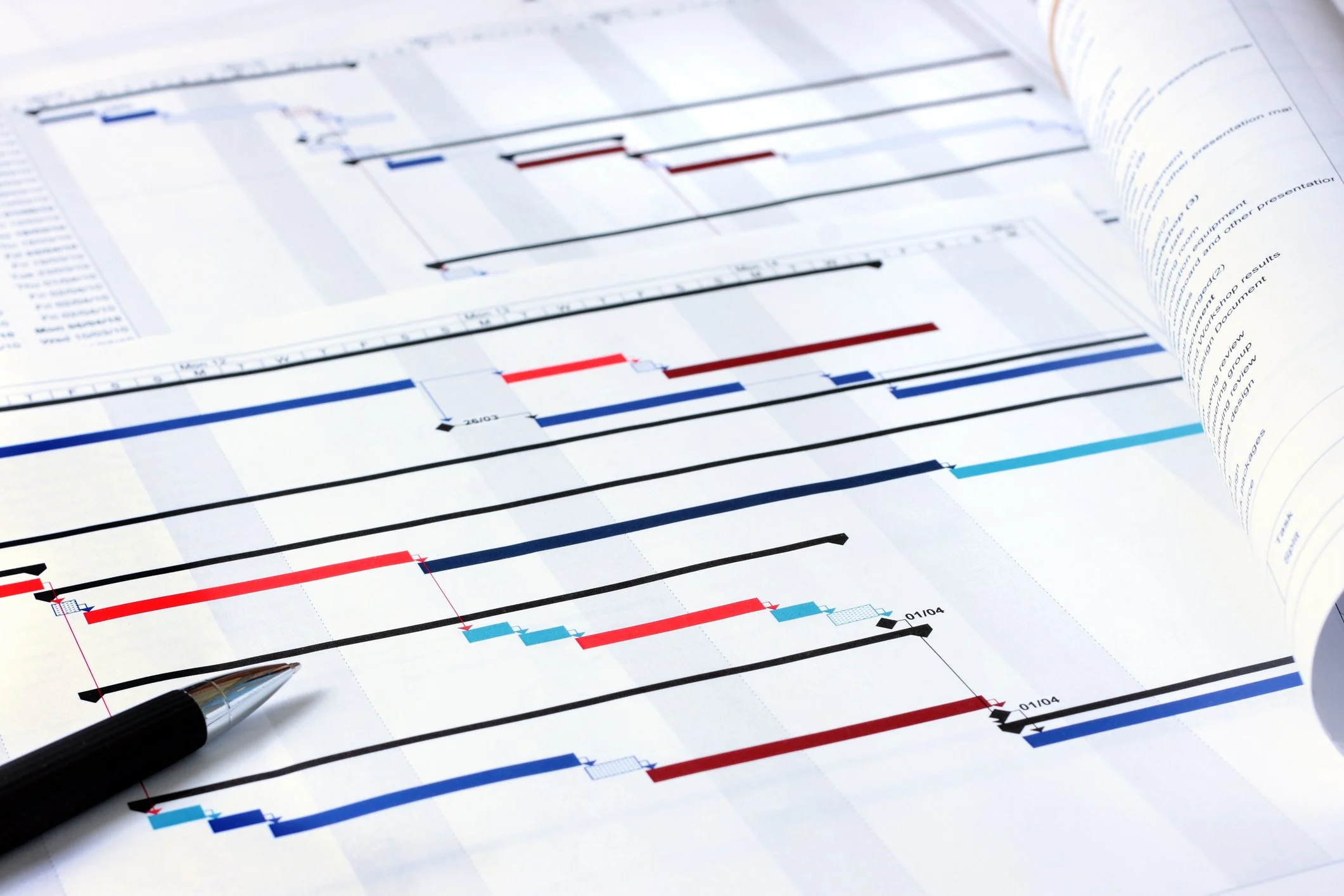 Diagramme de Gantt avec des barres colorées, une plume noire posée dessus.