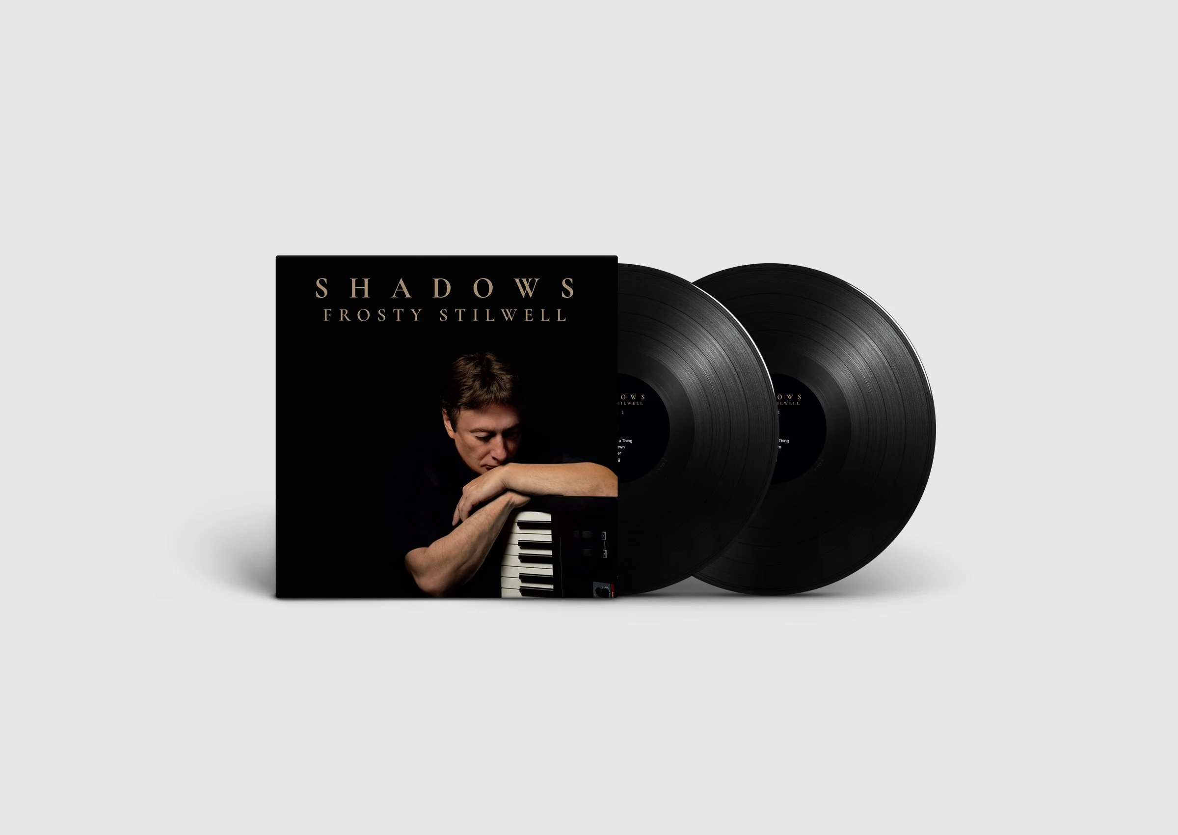 Album cover of 'Shadows' by Frosty Stilwell featuring a man resting his face on his arm, looking at a small keyboard, with two vinyl records next to the cover.