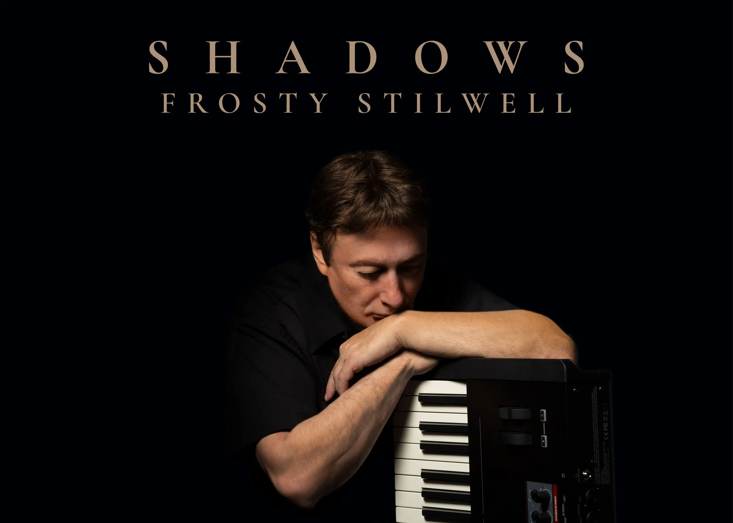 Cover of a music album titled 'Shadows' by Frosty Stilwell. The image features a person with short brown hair resting their head and arms on a keyboard synthesizer, looking contemplative, against a black background.