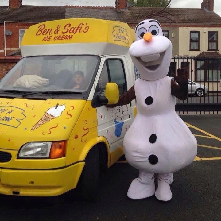 A person in a snowman costume standing next to a yellow ice cream truck with the sign 'Ben & Safi's Ice Cream' on top.