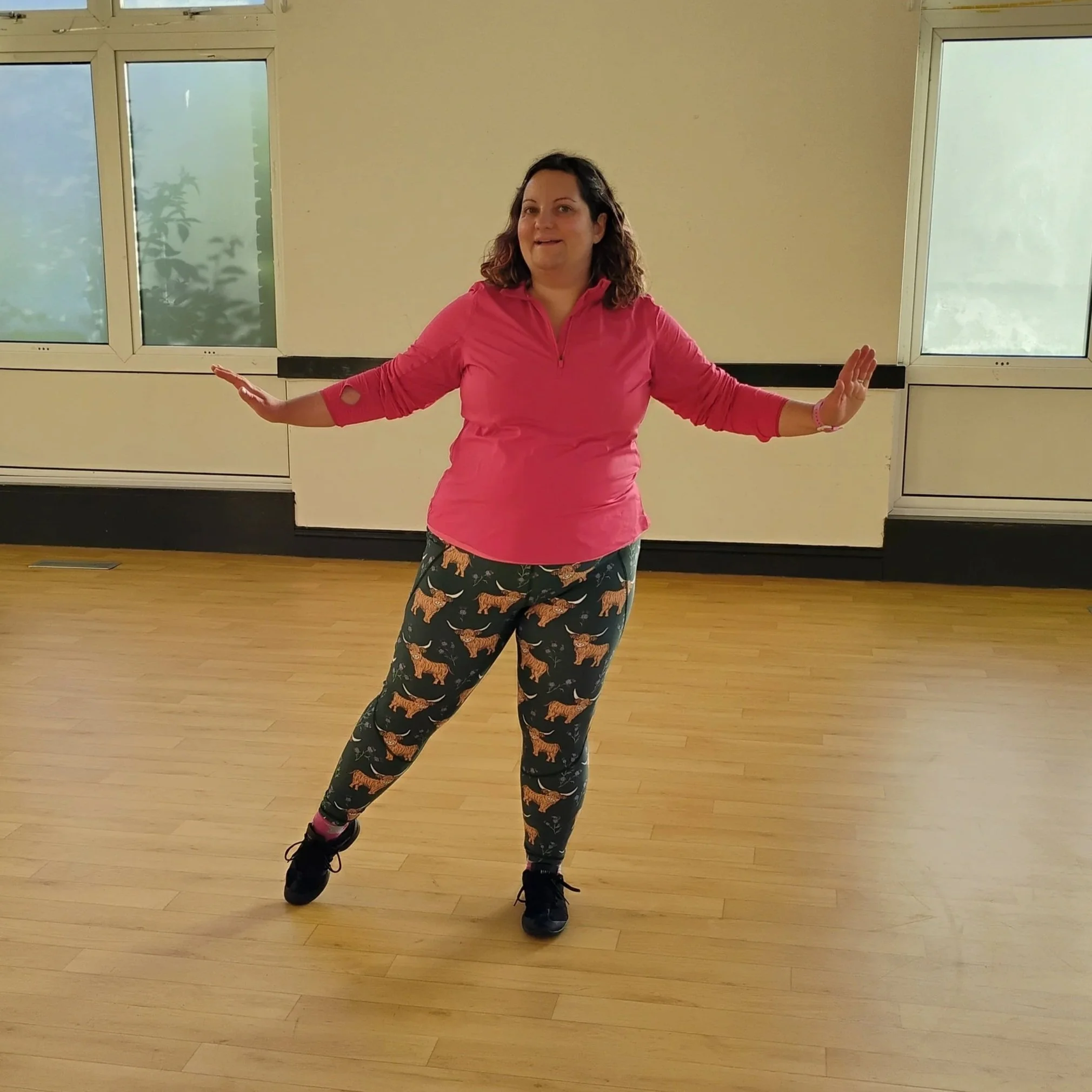fat, white, female instructor in dance pose with arms outstretched