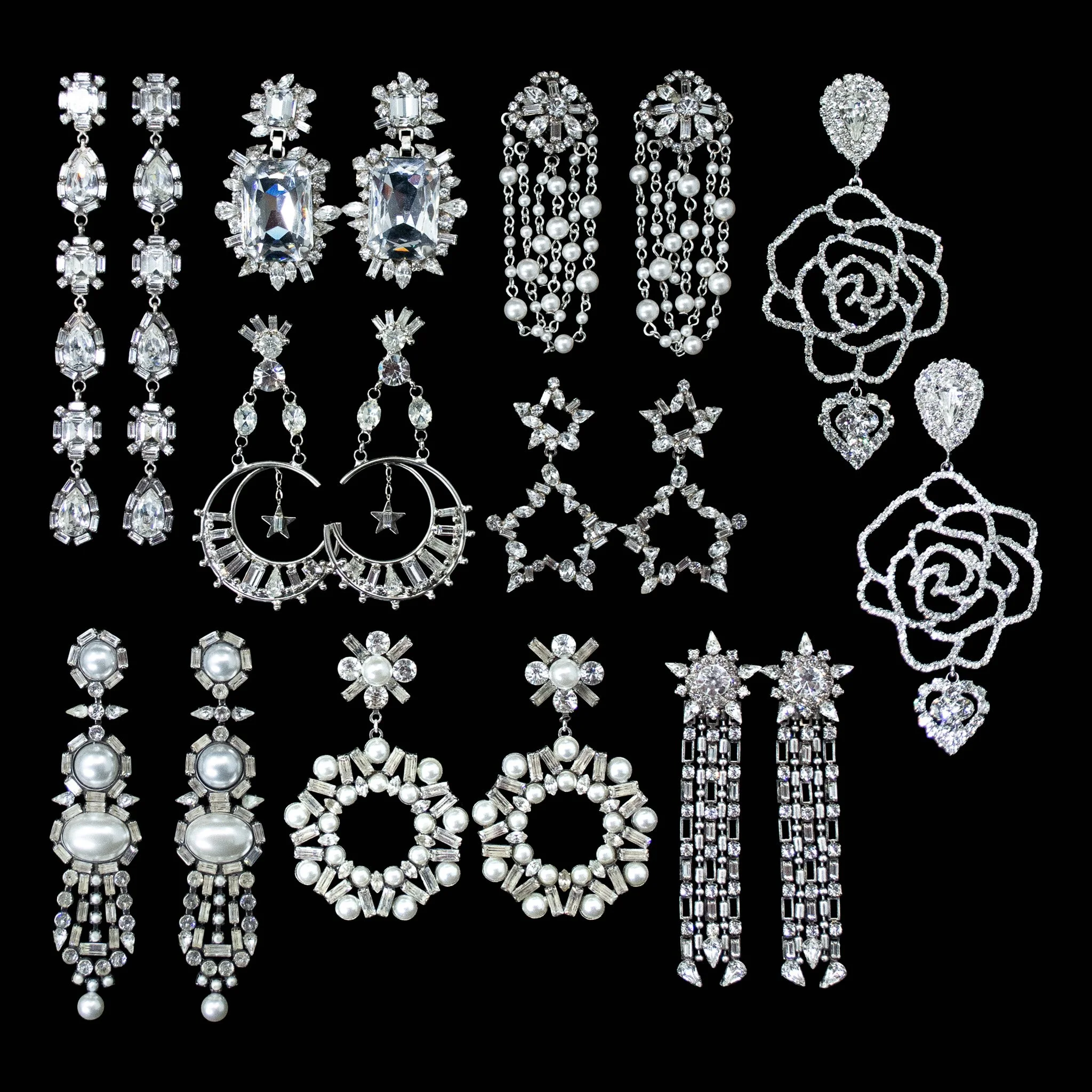 Collection of various silver and diamond jewelry pieces including earrings, necklaces, and brooches displayed on a black background.