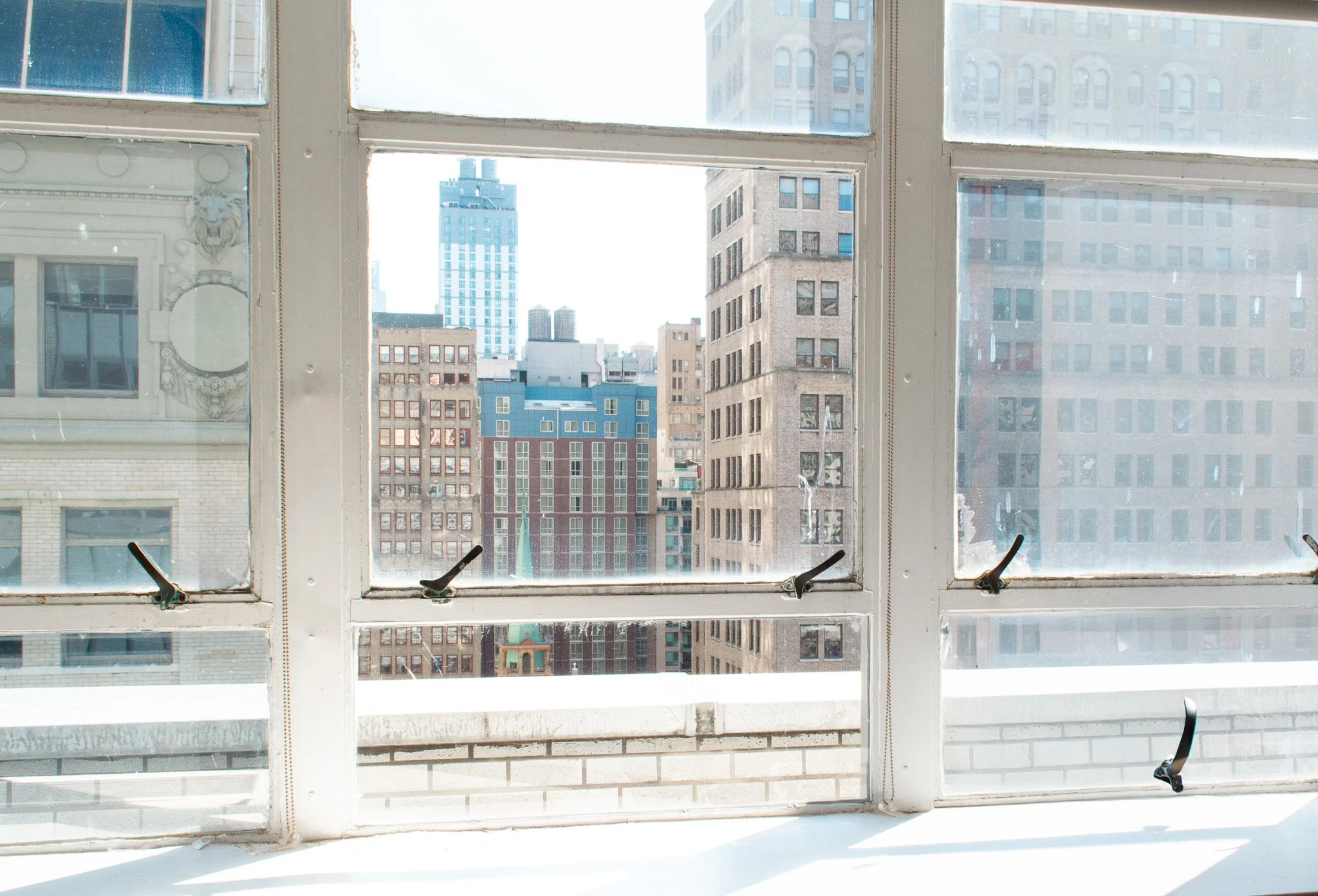 The office of custom jewelry manufacturer Manhattan Rhinestone, with a view of a city skyline through a multi-pane window with black window locks.