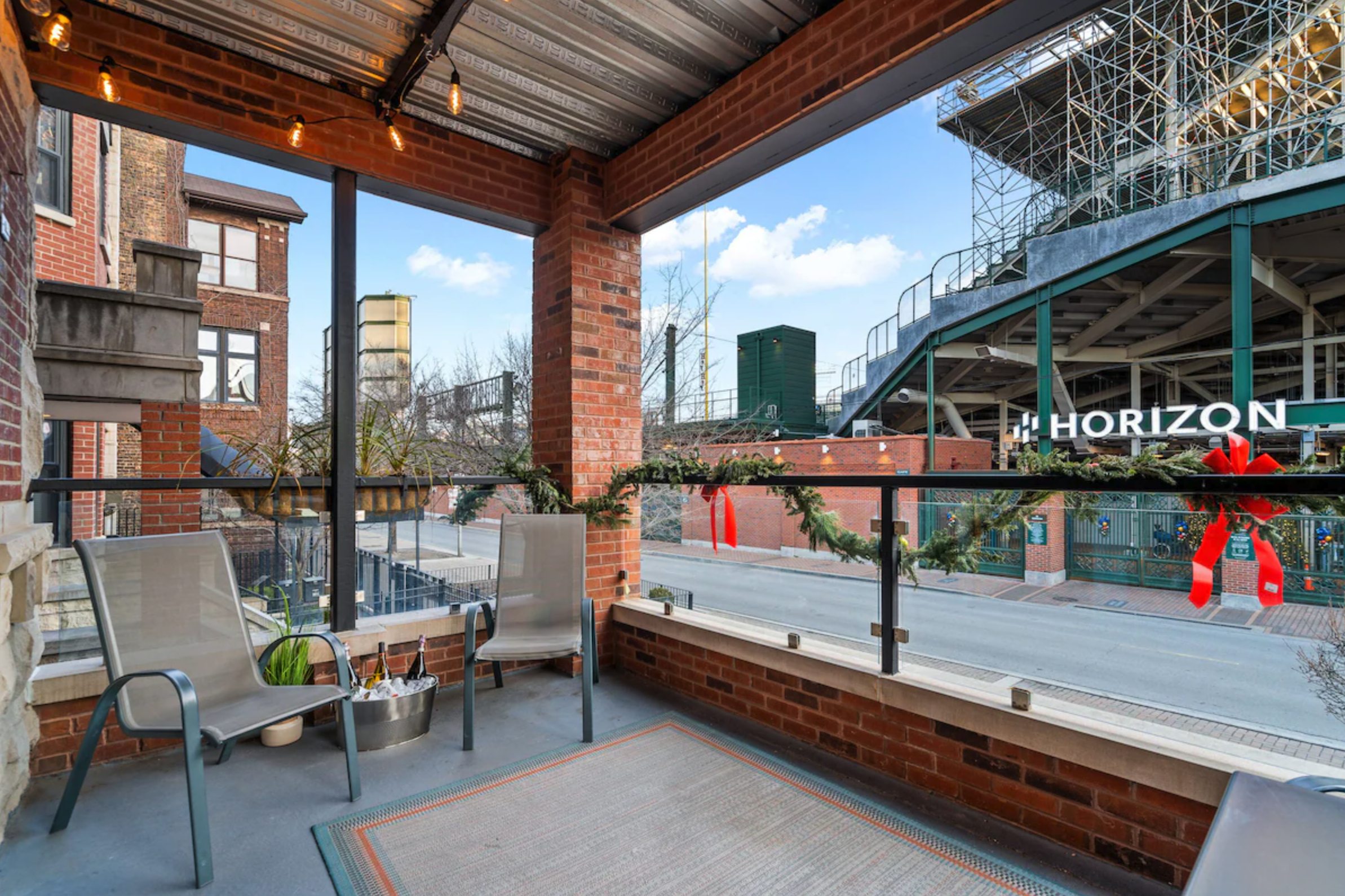 Group of five people having a meal on a rooftop deck in the city with tall buildings and string lights overhead