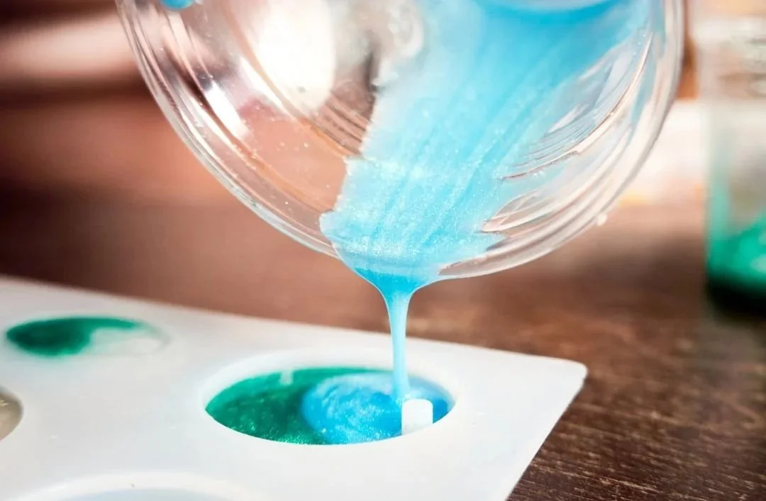 Blue liquid being poured into an ice cube tray.