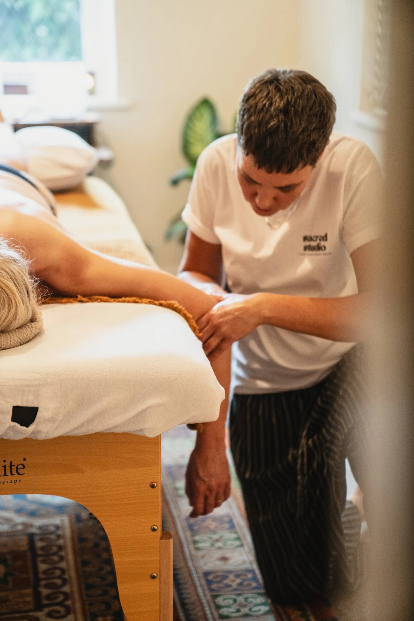 A person receiving physical therapy on their arm from a therapist in a well-lit room.