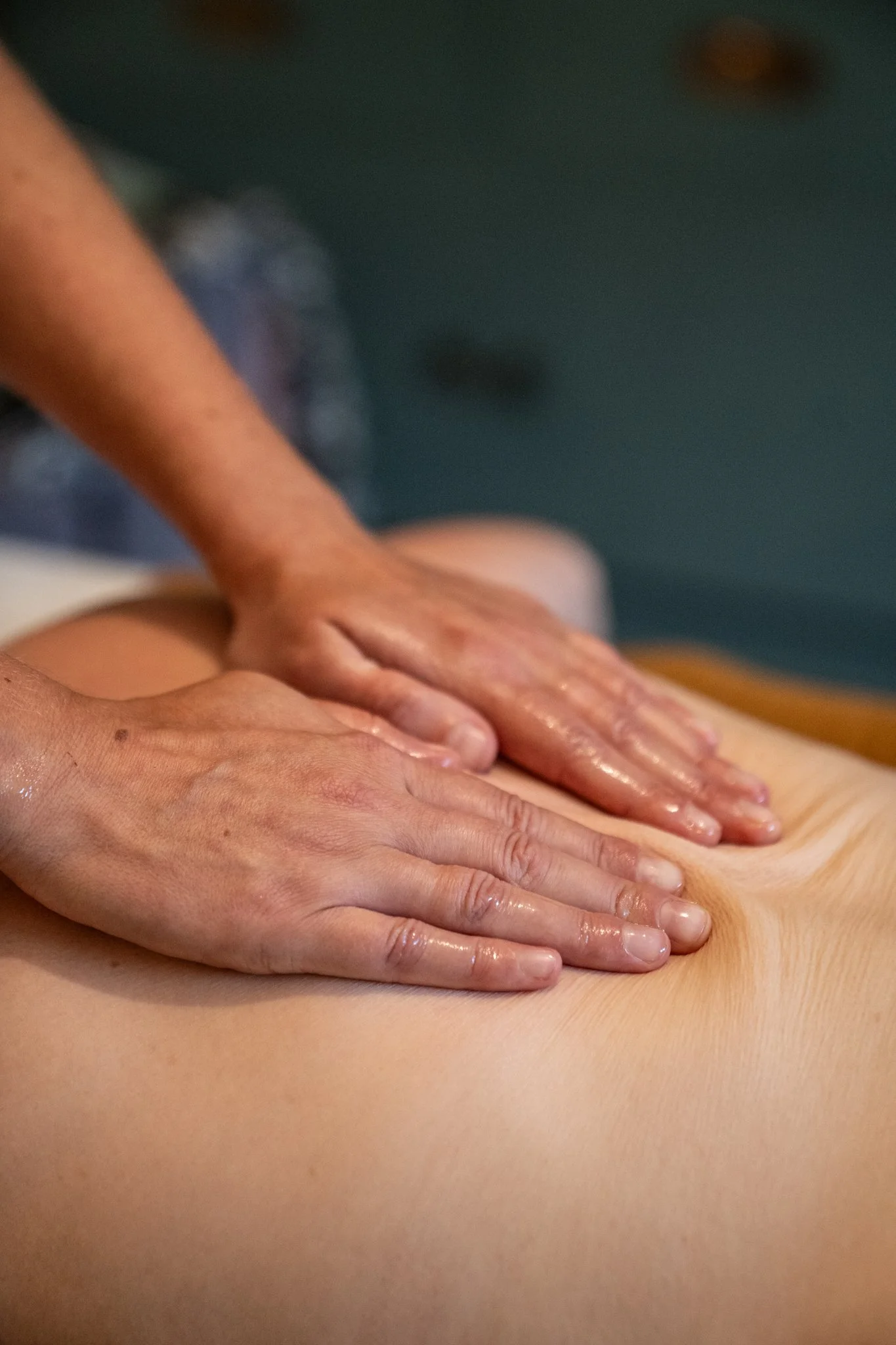 Hands performing a massage on a person's back in a massage therapy setting.