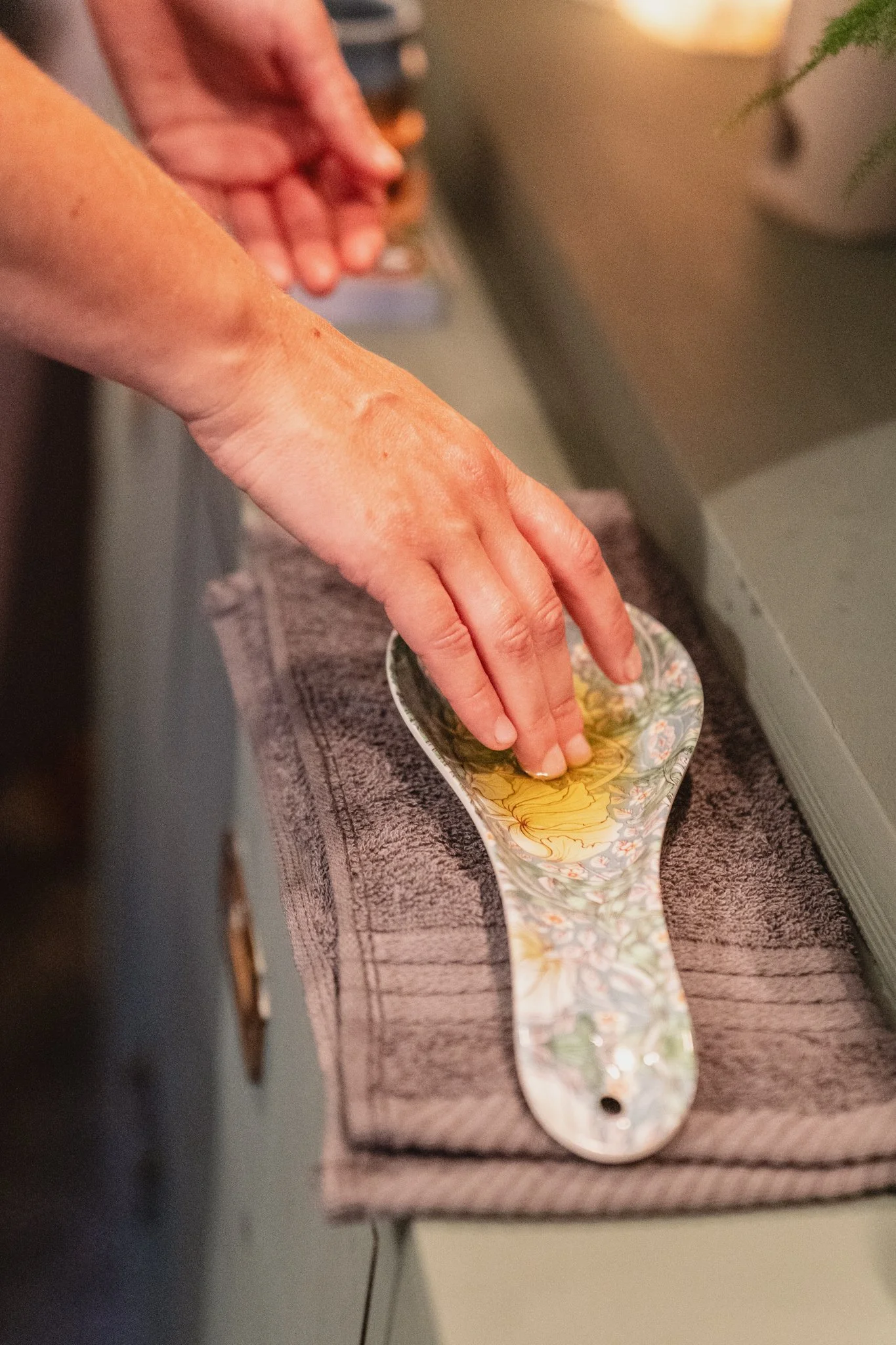 Person hand washing a decorative ceramic spoon with floral design under running water.