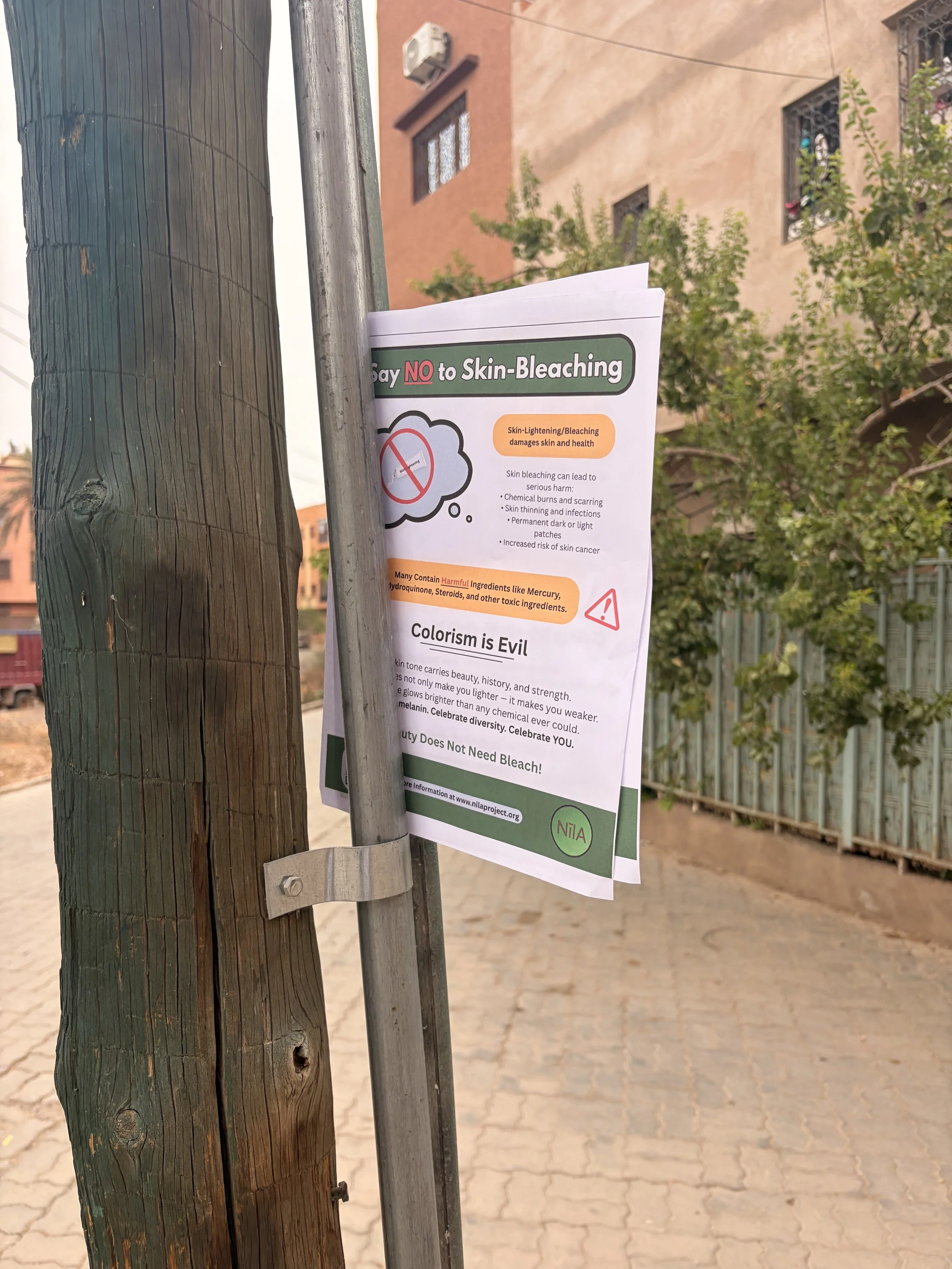 Sign attached to a utility pole with a message to say NO to skin-bleaching, explaining the health risks and harmful ingredients