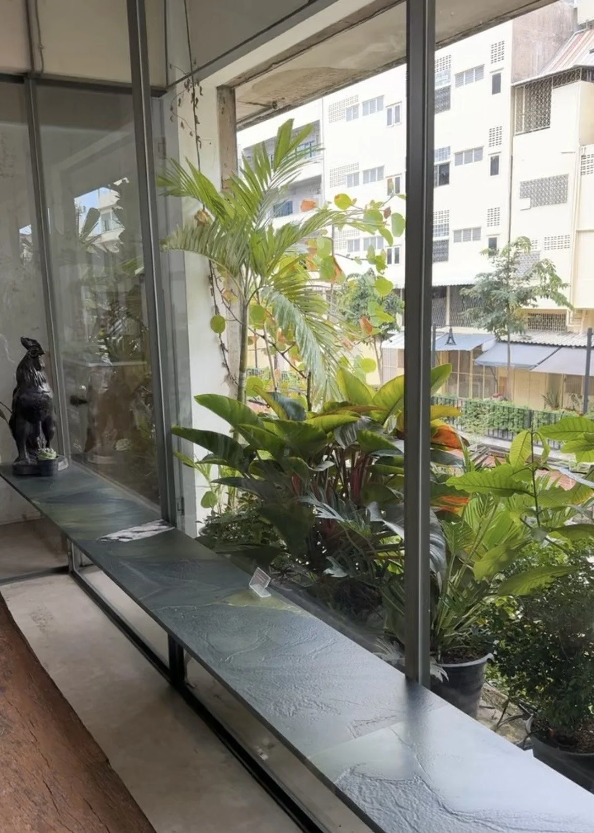 A large window overlooking the Khlong Ong Ang canal and greenery from inside the cafe