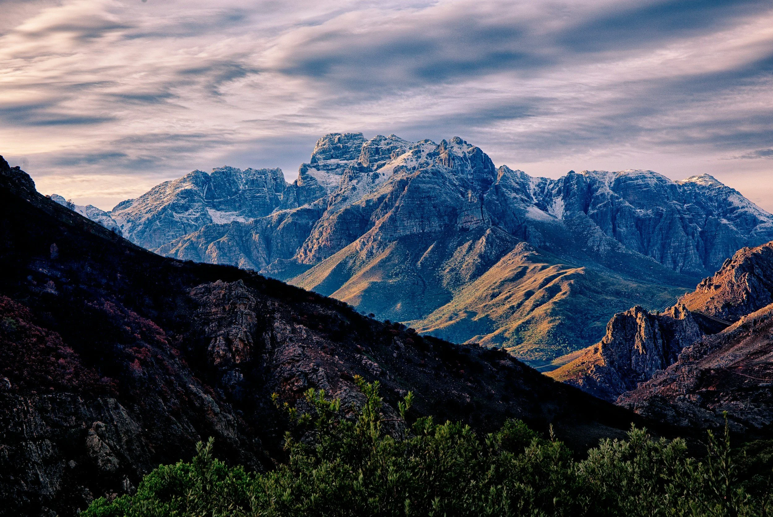 Mountain range with snow-capped peaks during cloudy sky in a scenic landscape.