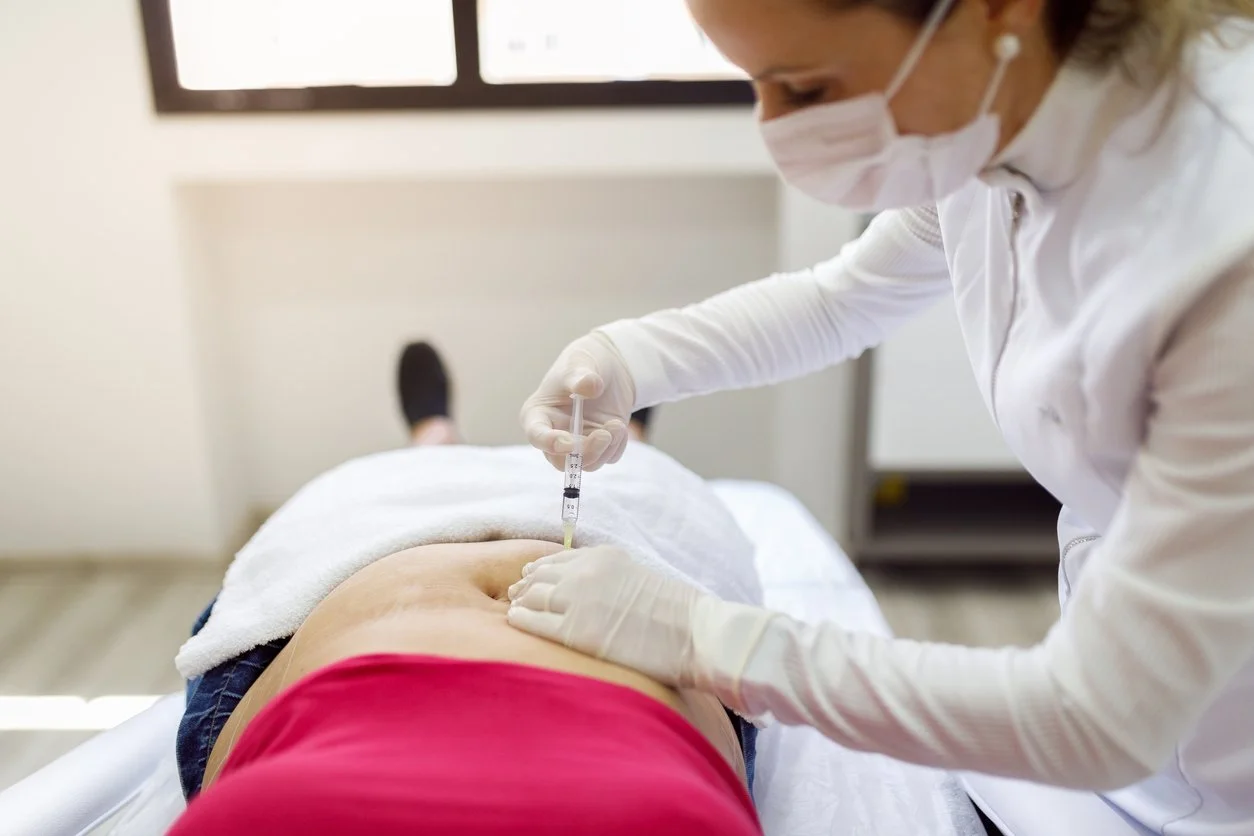 Aesthetician injecting a woman's stomach with semaglutide to help promote fat loss