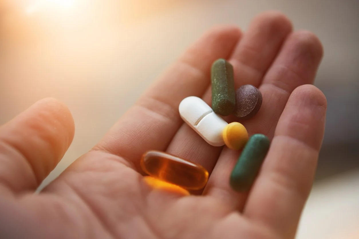 A person's hand holding an assortment of vitamins