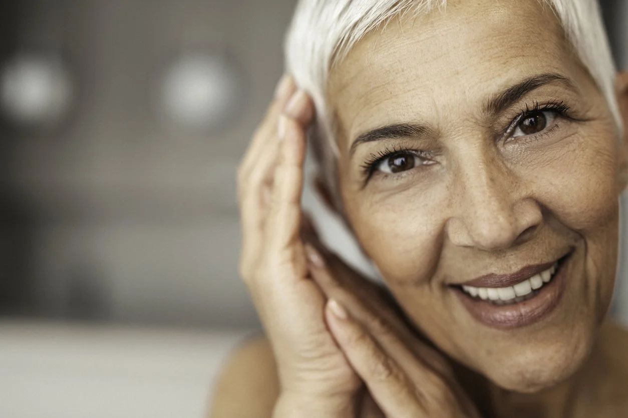 Older woman smiling and looking at the camera with hands next to face