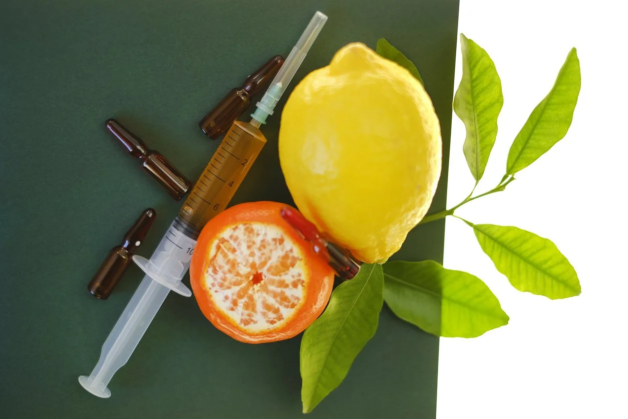 “Syringe and citrus fruits illustrating vitamin therapy and antioxidants