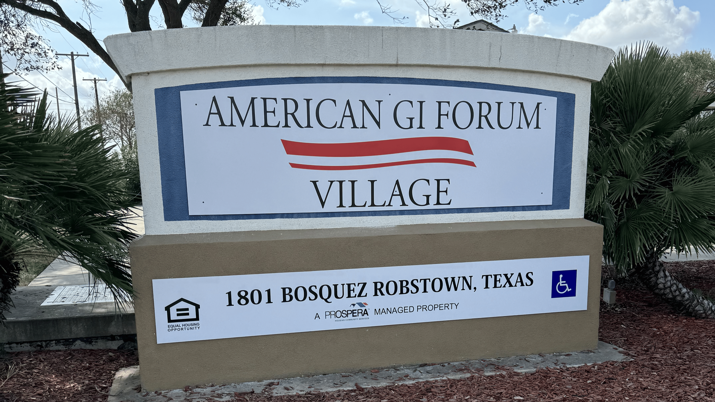 Sign for American Gi Forum Village at 1801 Bosquez Robstown, Texas, with symbols indicating accessibility features and equal housing opportunity.