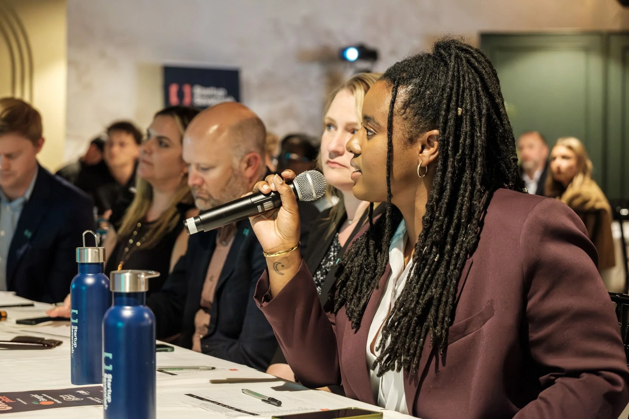 Destiny Mojica-Taylor sitting with a group of people speaking into a microphone at Start Up Savannah