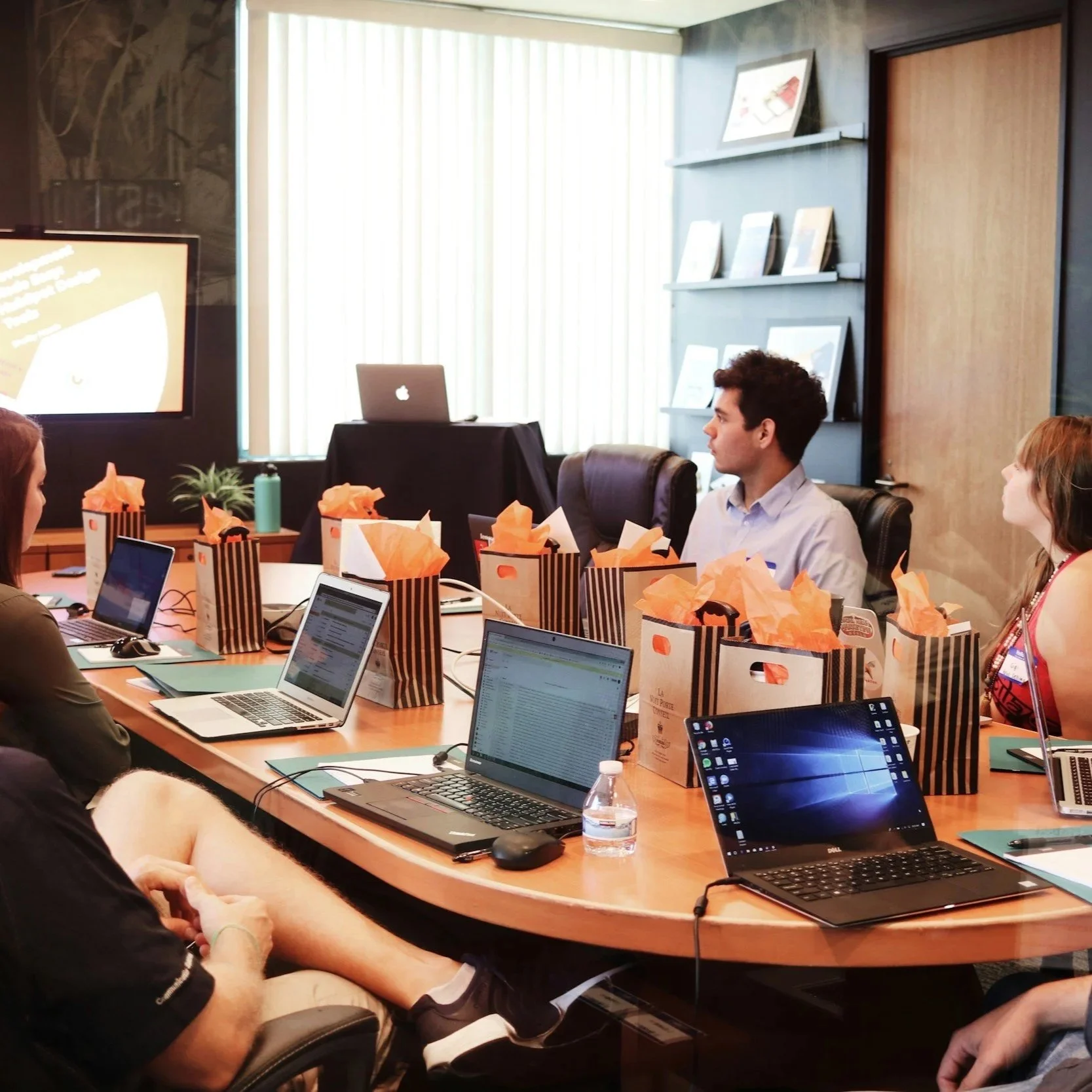 Group of people sitting around a table working on their laptops and talking amongst each other