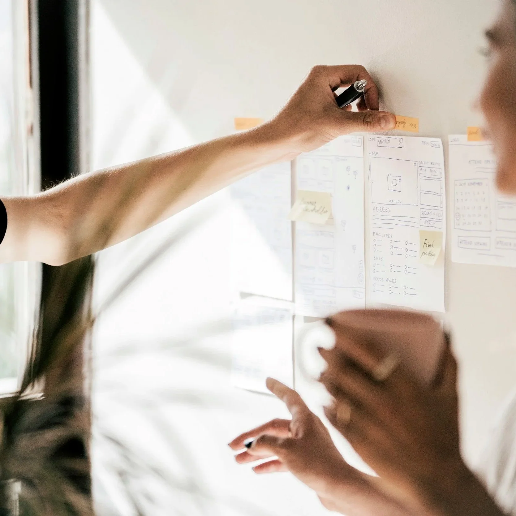 Person pasting a label above several papers while a second person talks with their hands