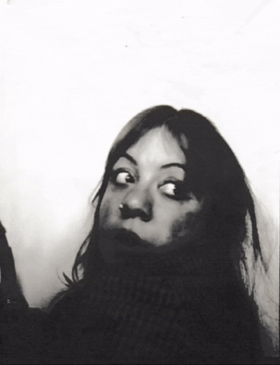 Black and white portrait of a woman with dark hair, looking over her shoulder with a neutral expression.