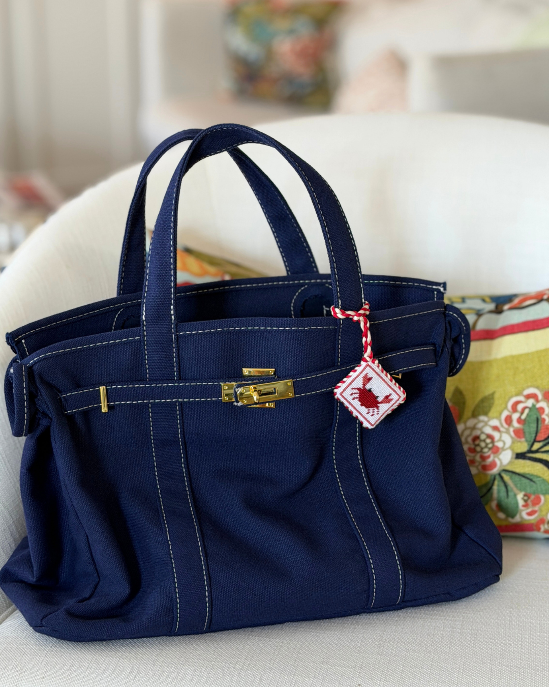 a finished crab needlepoint bag charm on a navy boatkin bag