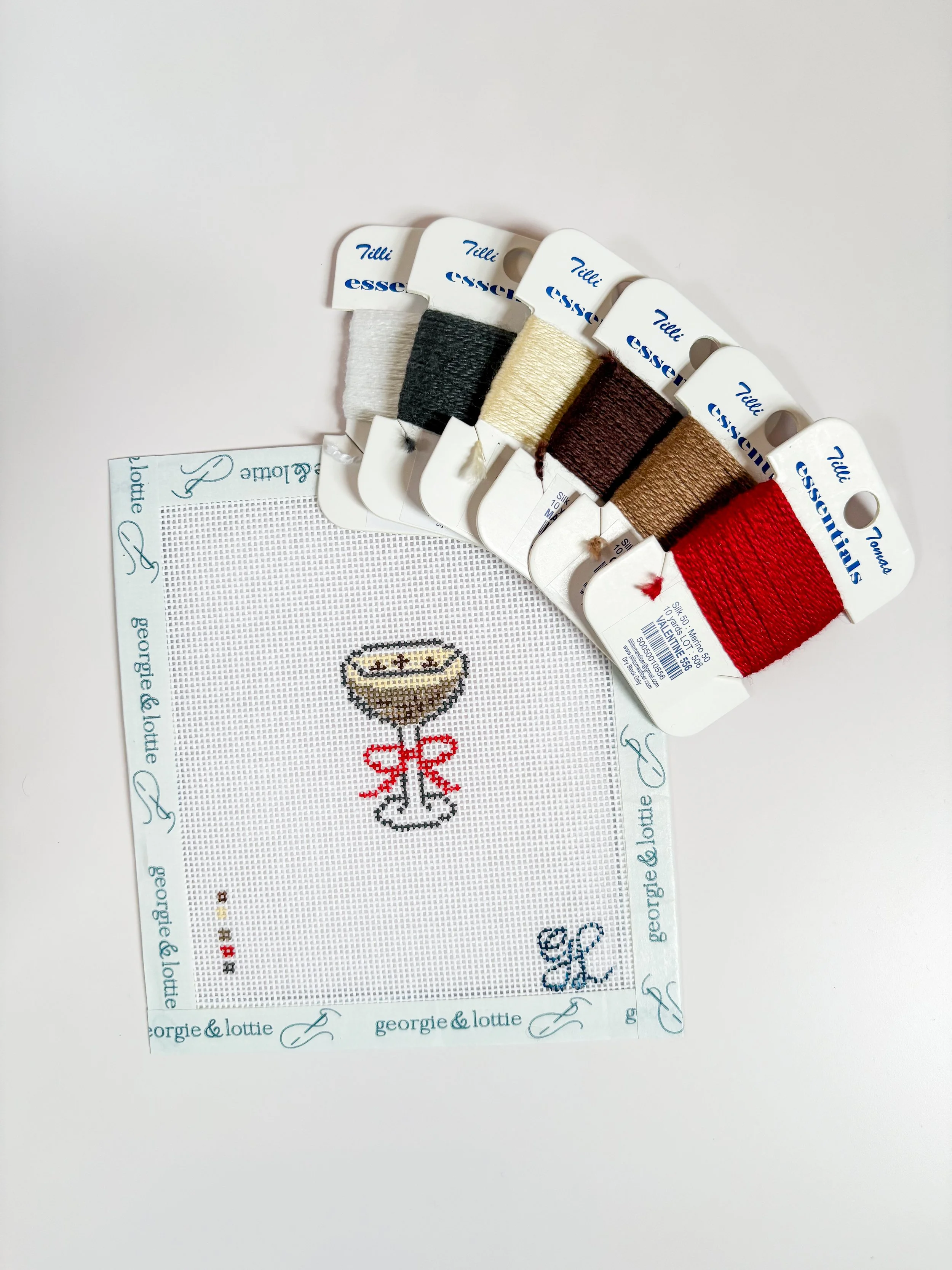 a needlepoint canvas with an espresso martini and threads