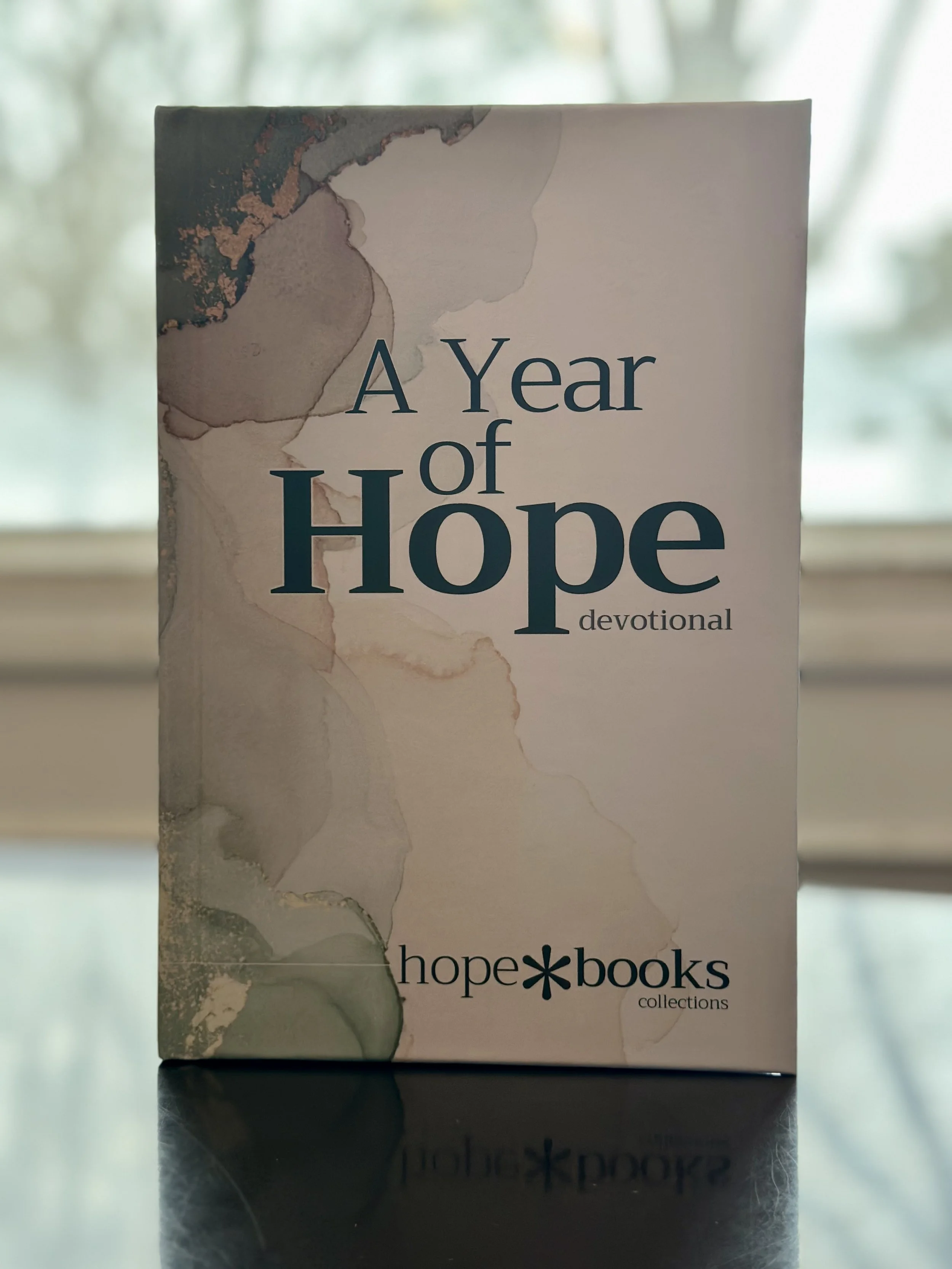 A neutral-toned wall with a leafy branch on the left, a small gray box and a candle on a white shelf, and a stack of books on the right. Overlaid text reads: 'New Collaboration Coming Soon'.