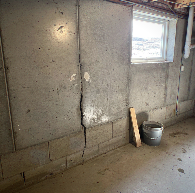 winter-thawed soil pressing cracked concrete foundation wall