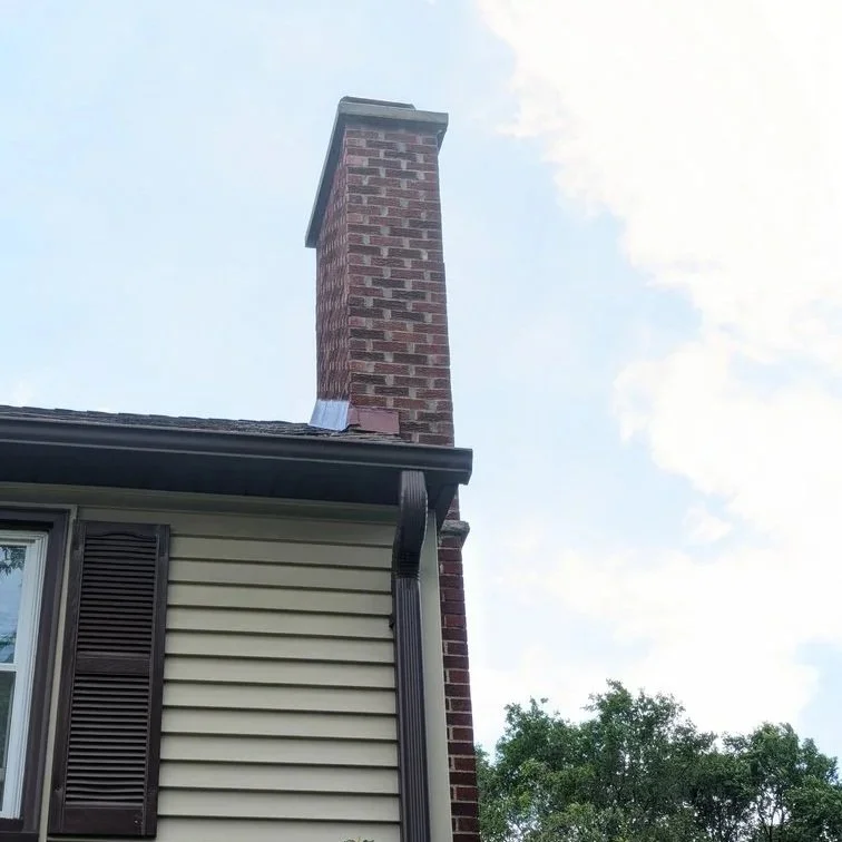 Chimney on a Minnesota home covered in snow and ice, showing exposure to harsh winter weather and freeze-thaw cycles.