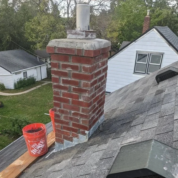 Minnesota homeowner inspecting a brick chimney for cracks and water damage caused by snow, ice, and freeze-thaw cycles.