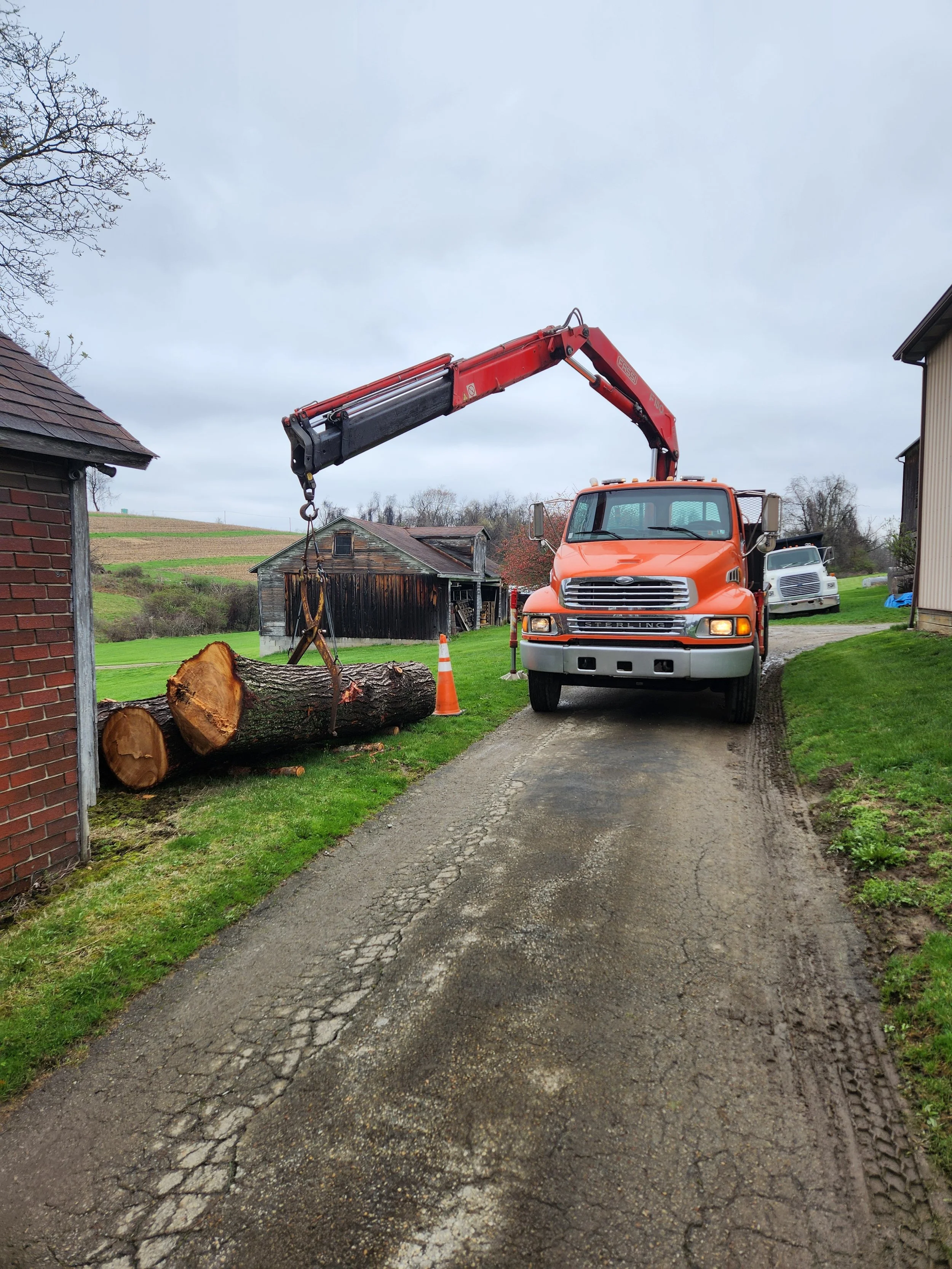 Crane truck lifting large tree logs during residential log removal and tree clearing by RPW Contracting in Jeannette, PA