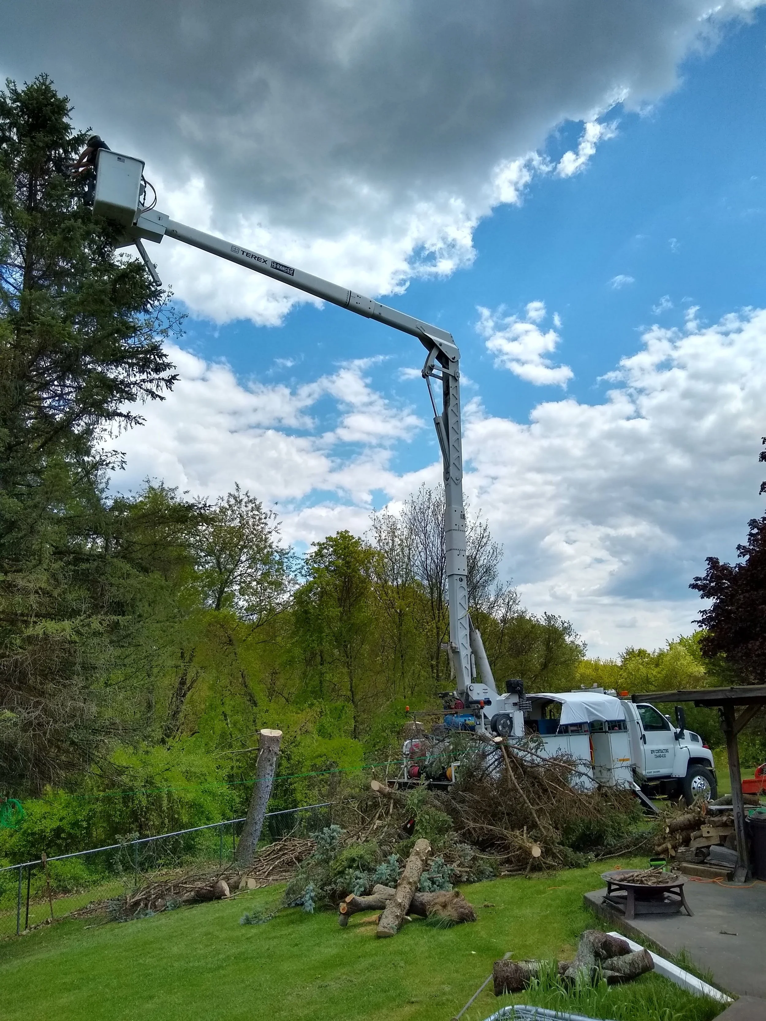 R.P.W. Contracting performing pine tree removal using bucket truck in residential yard in Jeannette, PA with emergency tree trimming and cleanup service