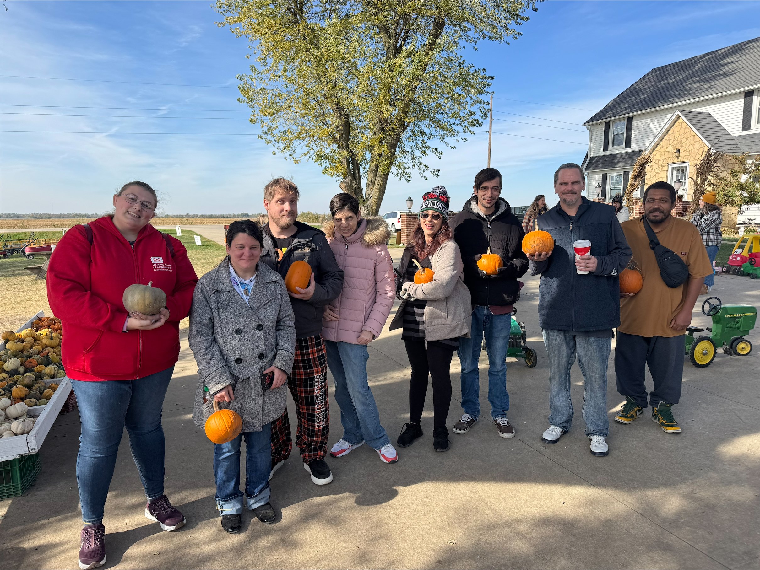 Group of people holding pumpkins at a pumpkin patch during fall.