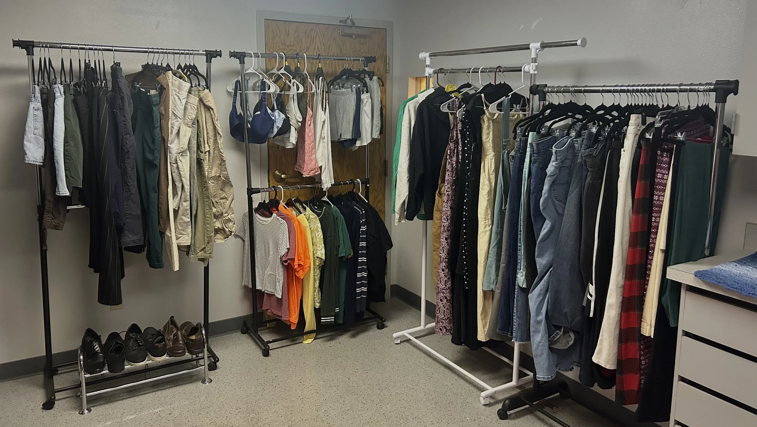 Clothing racks filled with various clothes including jeans, shirts, jackets, and accessories in a room.