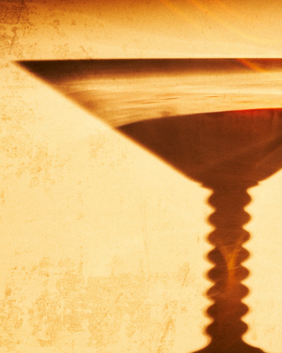 Close-up of a metal screw with a flat head casting a shadow on a beige textured surface.