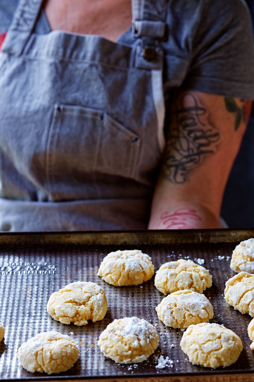 Uncooked cookie dough scoops on a baking sheet in a person's kitchen.