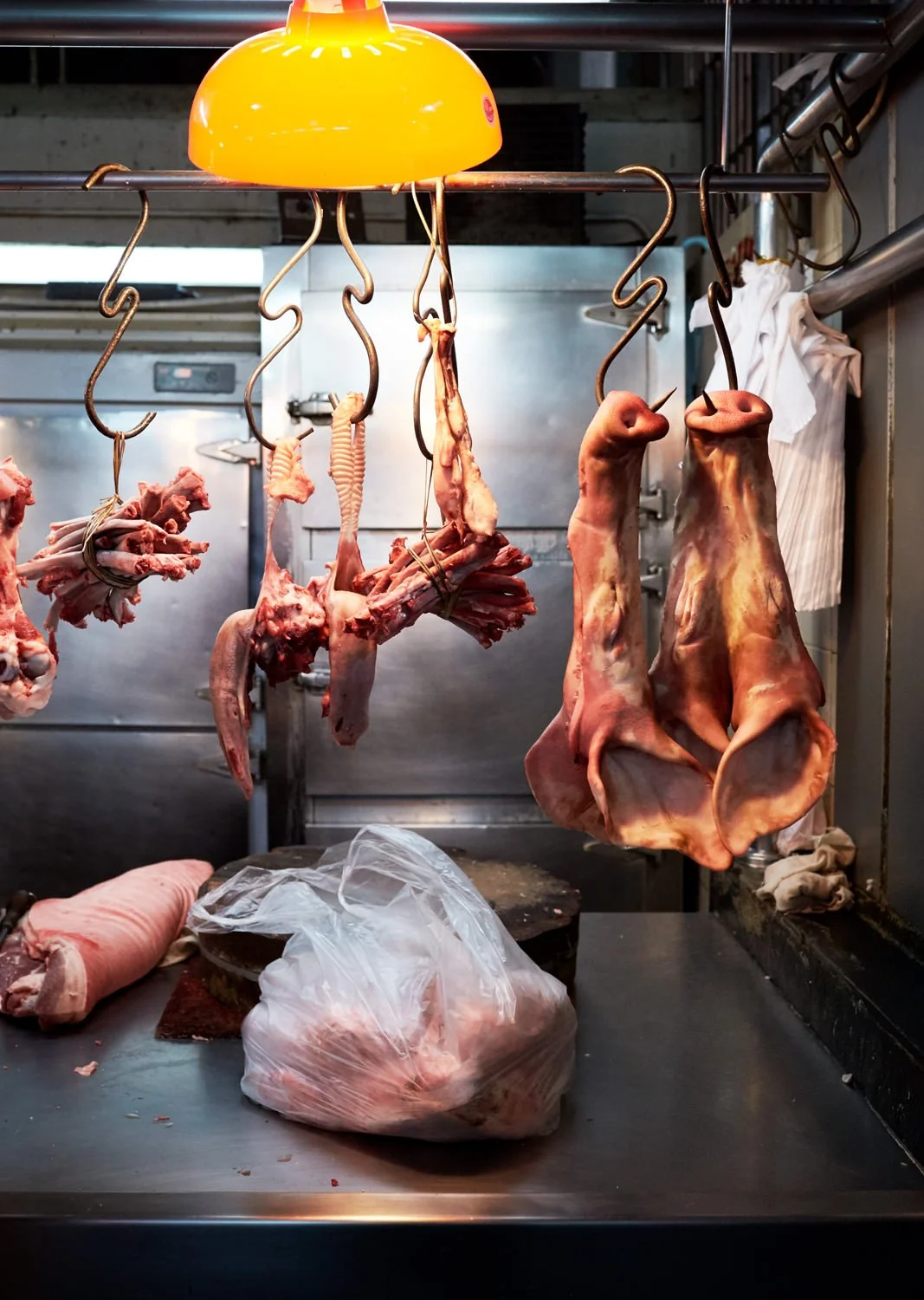 Hanging raw animal parts, including meat and organs, in a butcher shop or meat processing area.