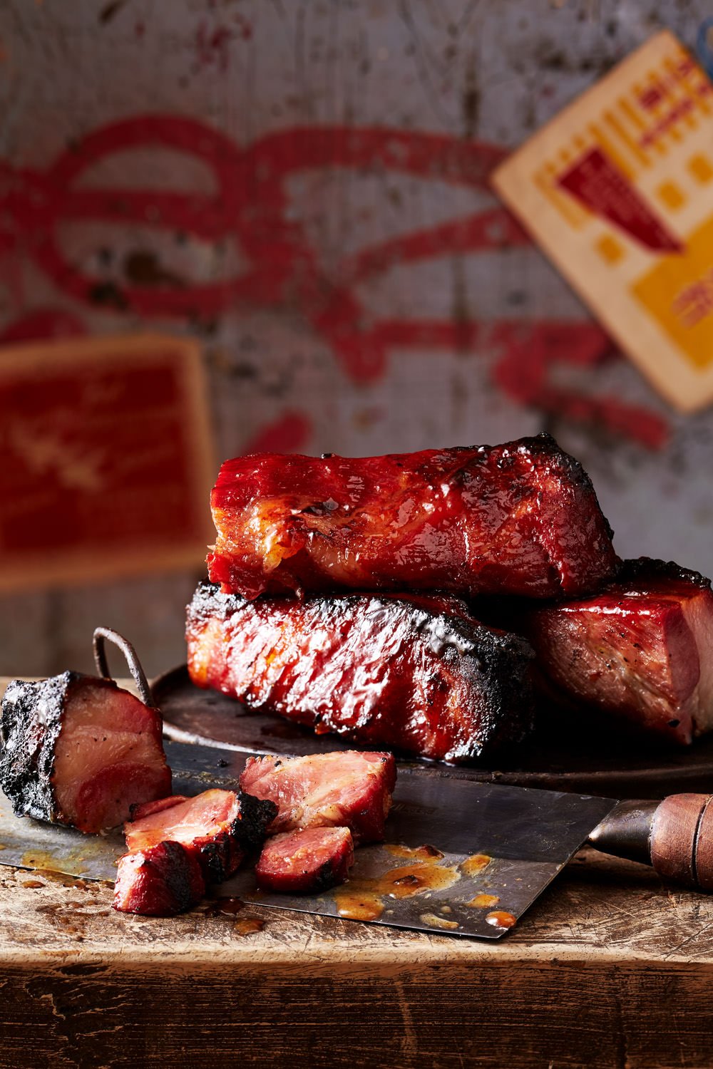 Stack of slow-cooked barbecued pork ribs on a wooden cutting board with some meat slices and juices