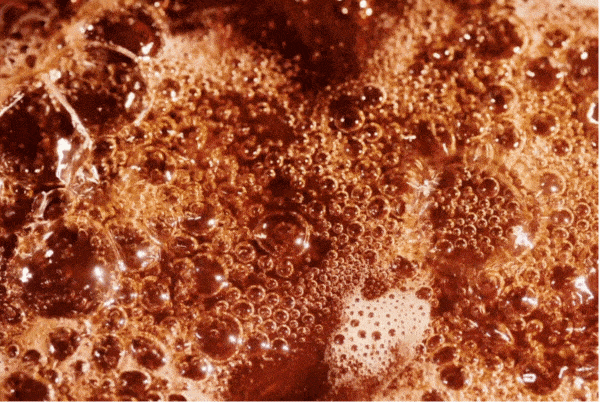 Close-up view of boiling and bubbling hot chocolate or coffee.