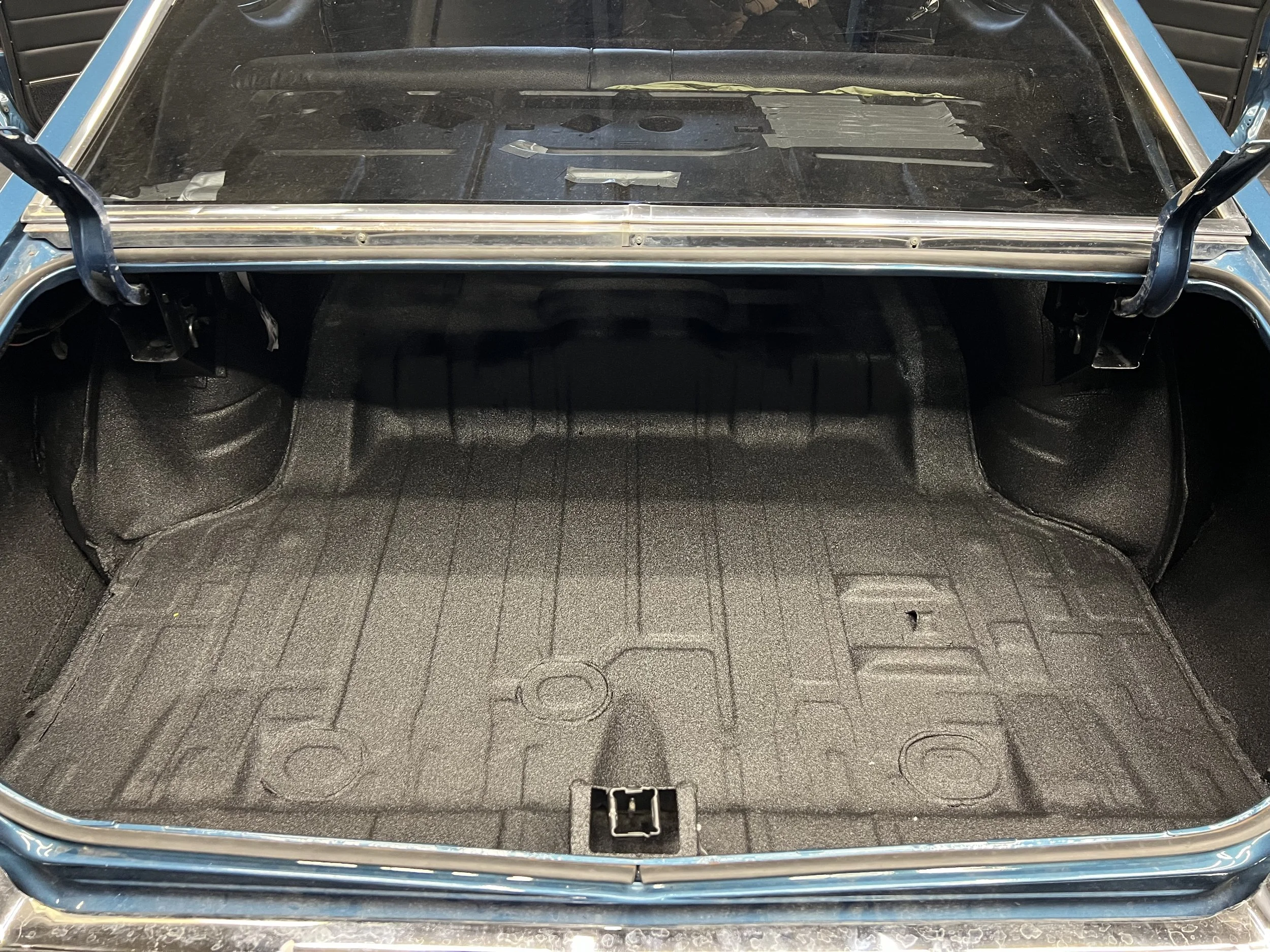 Empty car trunk with a textured black lining and a latch in the center.