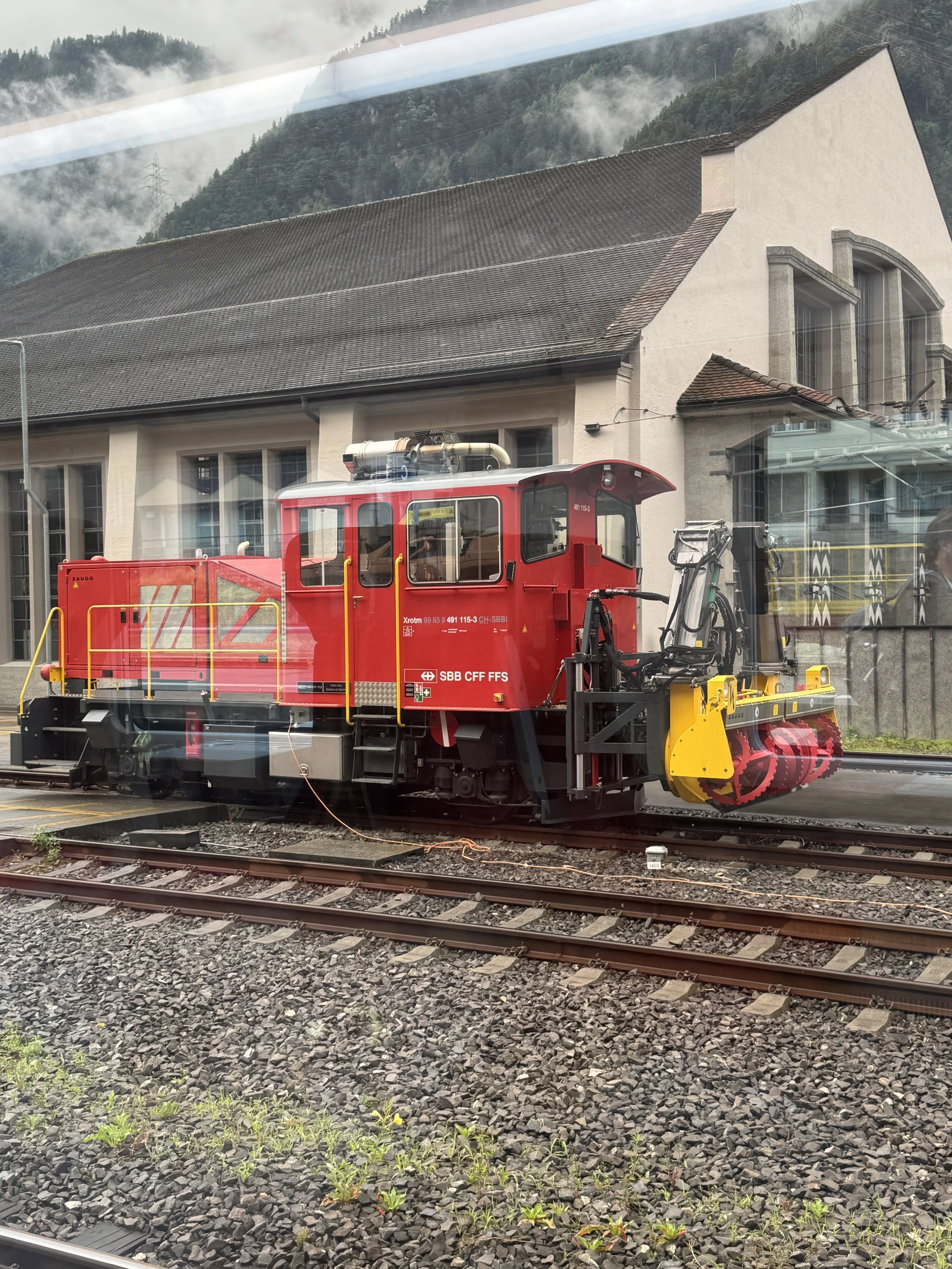 A photo of a snow plow made for train tracks parked in Andermatt, Switzerland, ready for the upcoming winter.