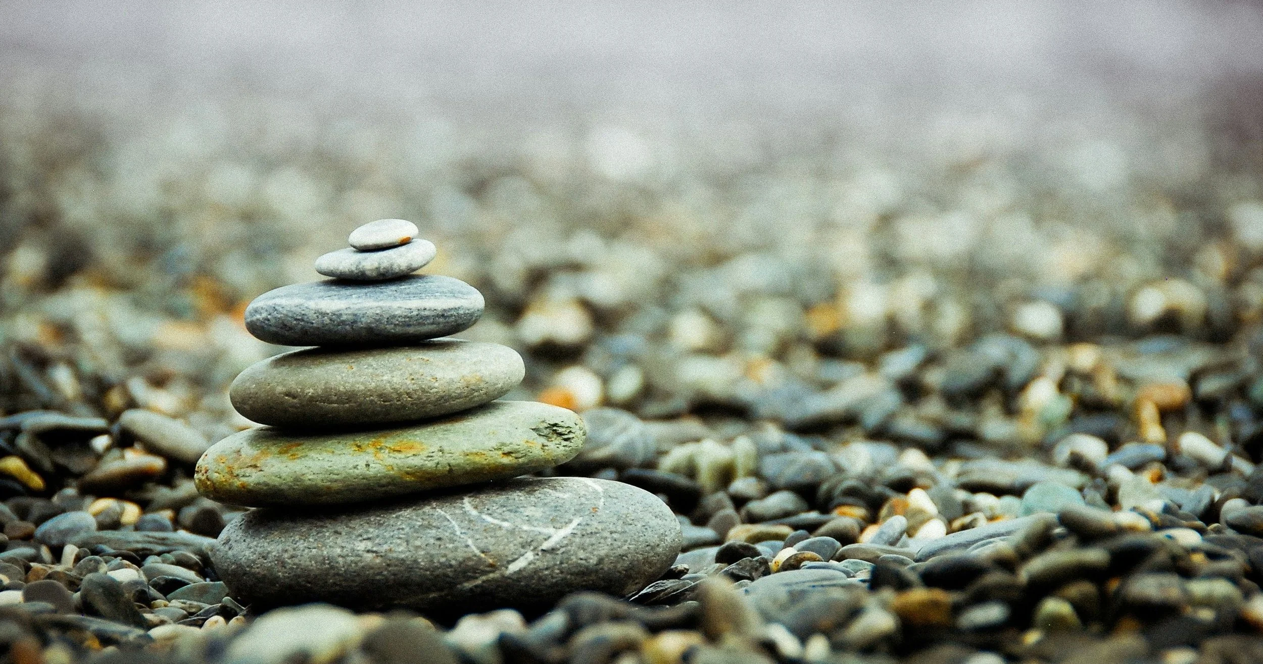 Stacked rocks balanced on a pebble-covered surface with a blurred background.