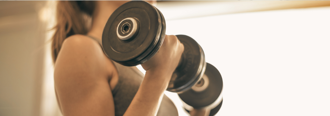 A woman lifting a dumbbell in a gym.