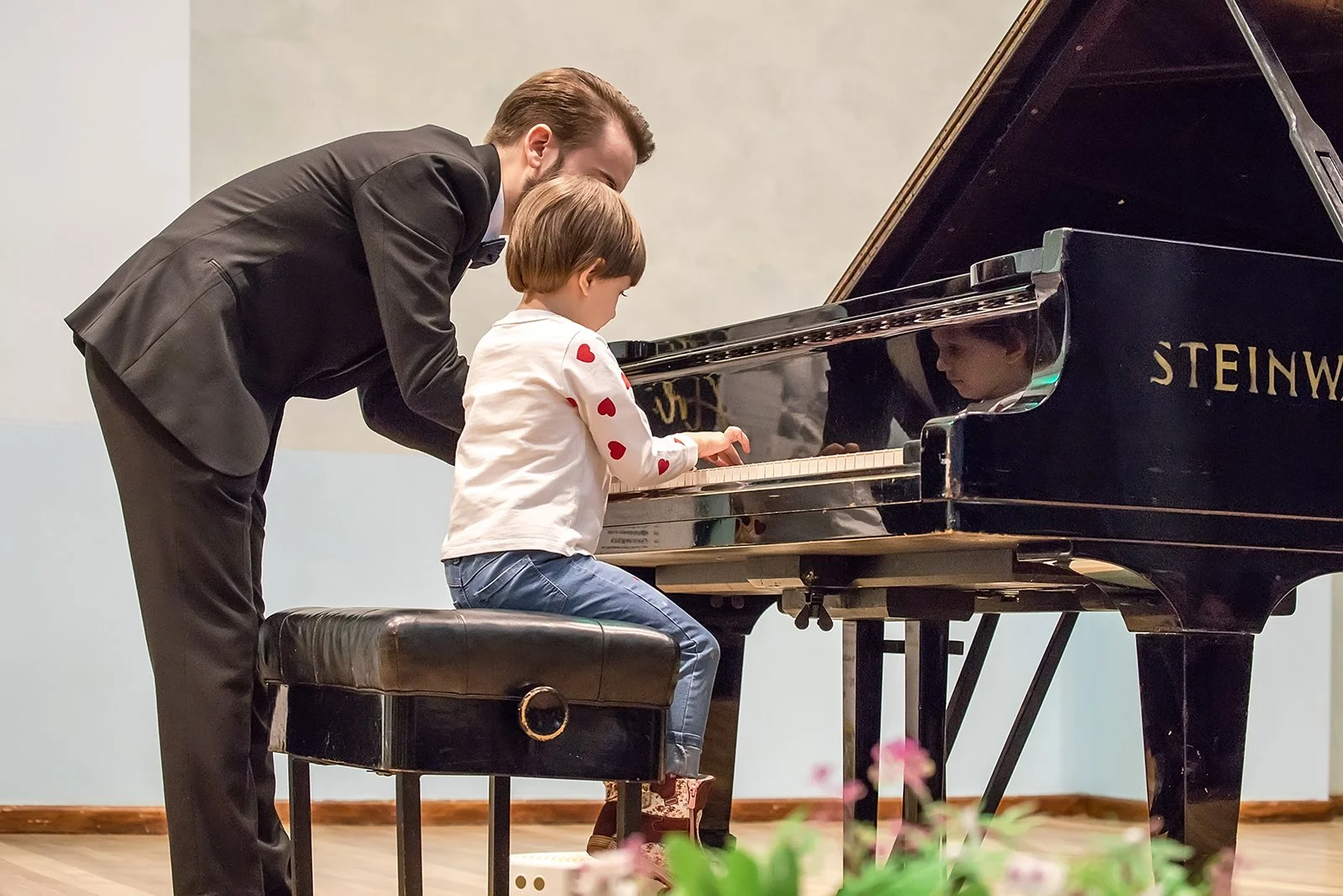 Professional piano teacher guiding a young child during a private piano lesson at a grand piano in Miami Beach