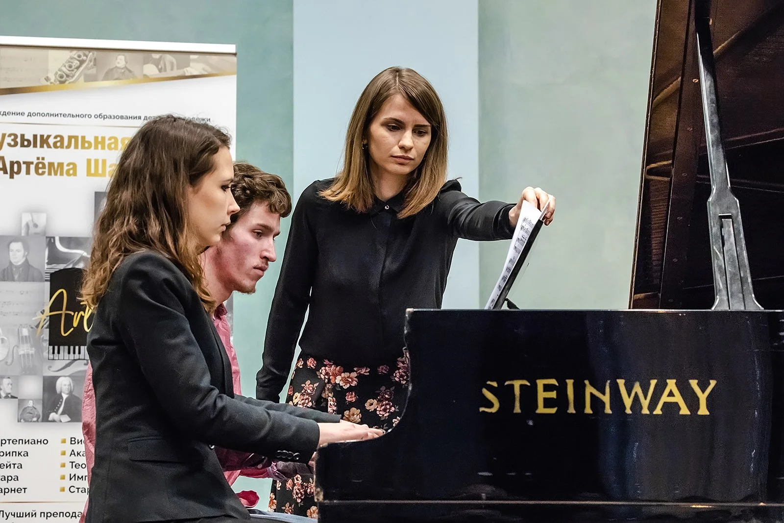 Professional piano instructor guiding adult students during a piano lesson at a Steinway grand piano