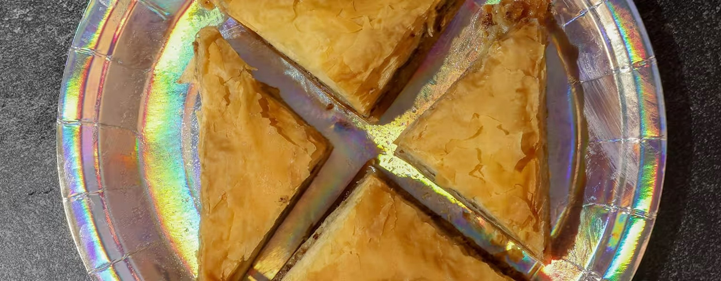 A glass plate with a colorful iridescent finish holding six slices of a layered cake with a golden brown top and a filling.