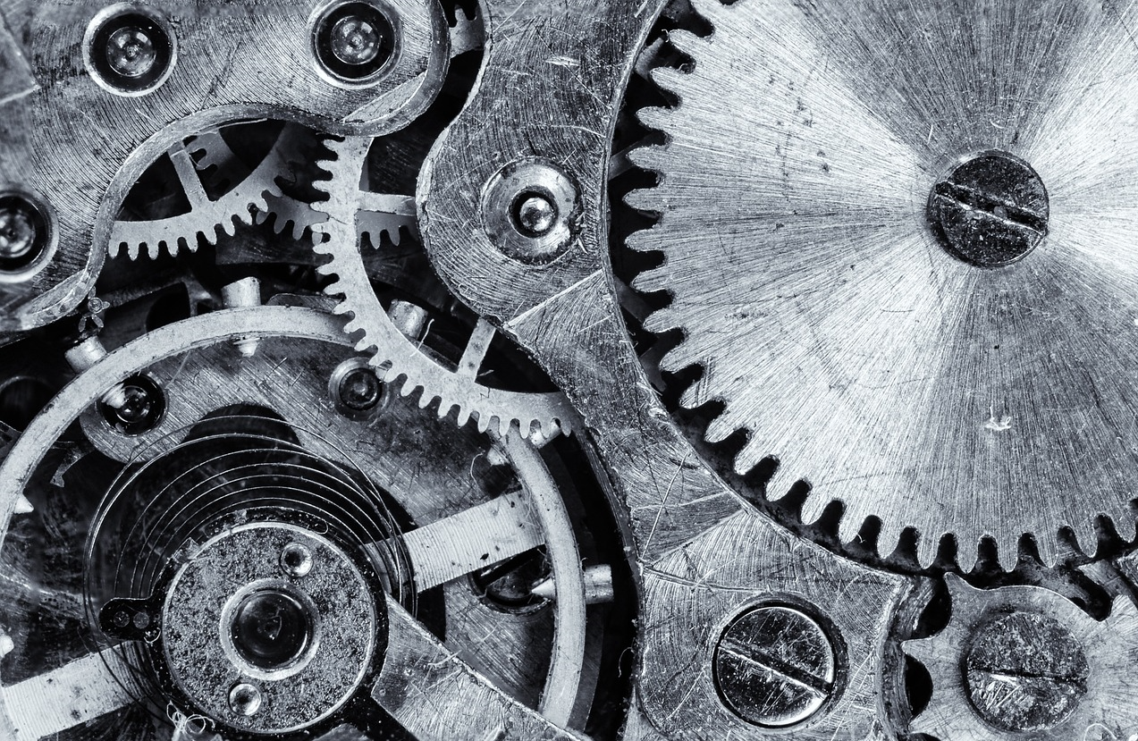 Close-up of interlocking metal gears and cogs in black and white.