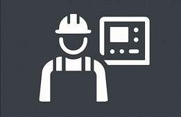 Icon of a smiling worker wearing a hard hat and overalls, standing next to a control panel or machine.
